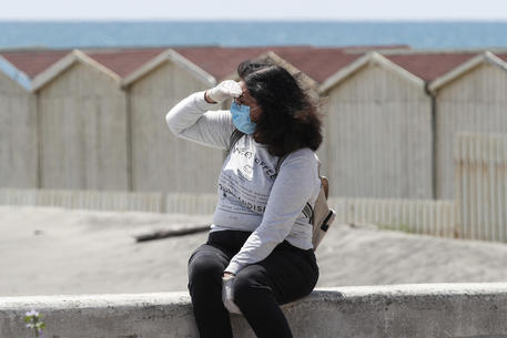 Una donna con la mascherina in spiaggia a Ostia © ANSA
