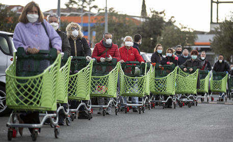 Fila di persone con i carrelli della spesa in attesa di entrare nel supermercato ed evitare così la contemporanea presenza di troppi clienti all'interno. Roma, 27 marzo 2020 © 