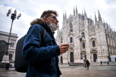 Un passante con la mascherina davanti al Duomo di Milano © AFP