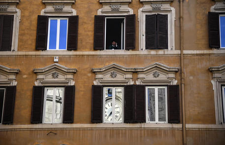 L'orologio sulla facciata di Palazzo Montecitorio riflesso nella finestra di un edificio durante le consultazioni del presidente incaricato Fico © ANSA