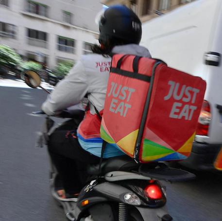Un rider della Just Eat impegnato in una consegna nel centro di Genova © ANSA