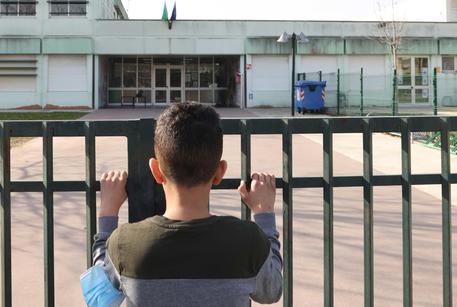 Un ragazzino osserva il suo plesso scolastico, chiuso per la pandemia © ANSA