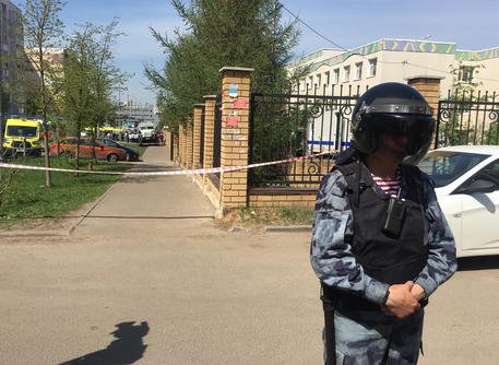 Un poliziotto russo davanti alla scuola presa d'assalto a Kazan in Russia © EPA