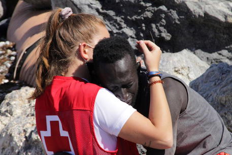 Una volontaria della Croce rossa abbraccia un migrante senegalese a Ceuta © EPA