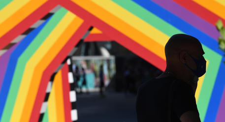 Una persona osserva un'installazione con i toni arcobaleno del Pride per celebrare la comunità  Lgbtqi esposta in piazza Gae Aulenti © ANSA