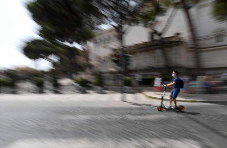 Un ragazzo guida un monopattino in via dei Fori Imperiali a Roma © ANSA