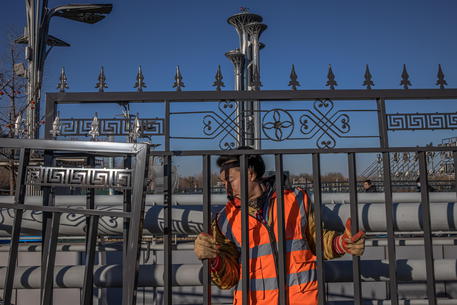 Un operaio monta un cancello davanti alla Olympic Tower di Pechino © EPA