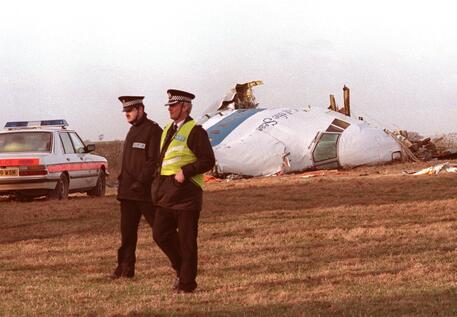 Due poliziotti il 21 dicembre 1988 passano davanti a quello che resta del Pam Am Boeing 747 © ANSA