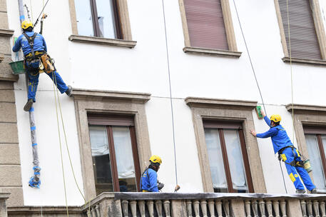 Operai acrobati al lavoro su un facciata di un palazzo a Milano © ANSA