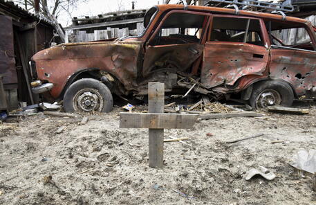 La carcassa di un'auto con davanti una croce in una casa privata a Gostomel © EPA