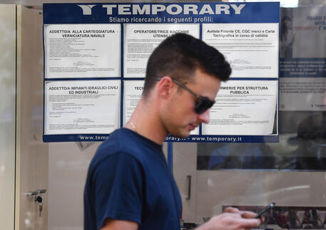 Un giovane passa davanti una vetrina di un'agenzia di lavoro interinale © ANSA