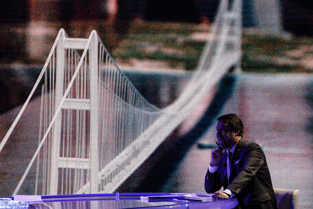Il ministro dei trasporti Matteo Salvini e, dietro, un rendering del ponte sullo stretto © ANSA