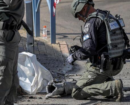 Militari israeliani con i resti di un razzo intercettato dal sistema di difesa © AFP