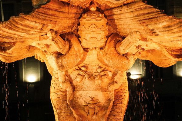 The Tritone's Fountain is illuminated in orange