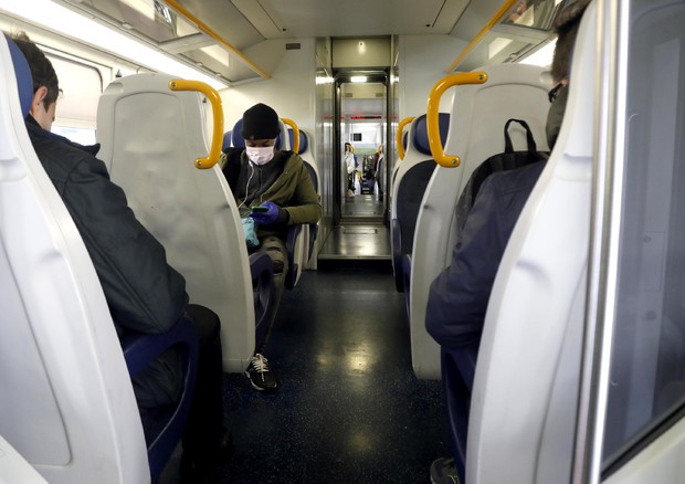 Un uomo con la mascherina su un treno regionale a Milano © ANSA