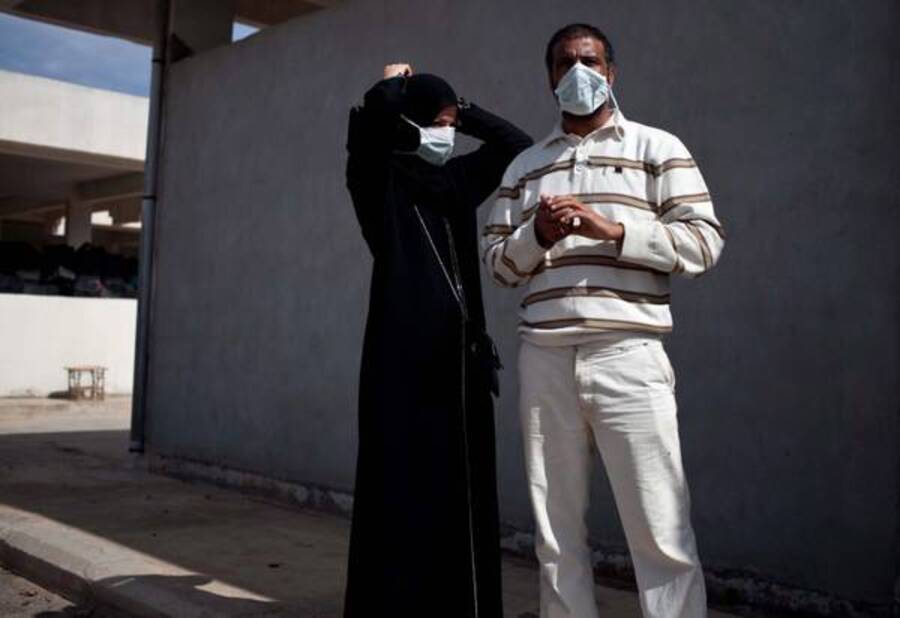 Due persone mettono una mascherina prima di entrare nel mercato africano di Misurata a vedere il corpo di Muammar Gaddafi © Ansa