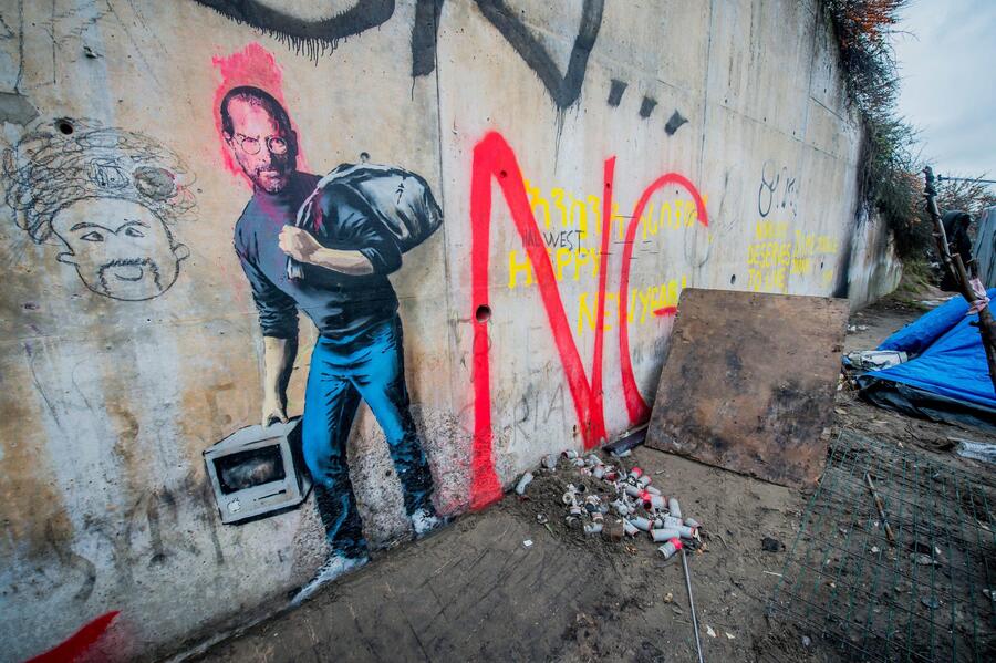 Il murales di Steve Jobs visto da Banksy all'ingresso del campo profughi di Calais © Ansa