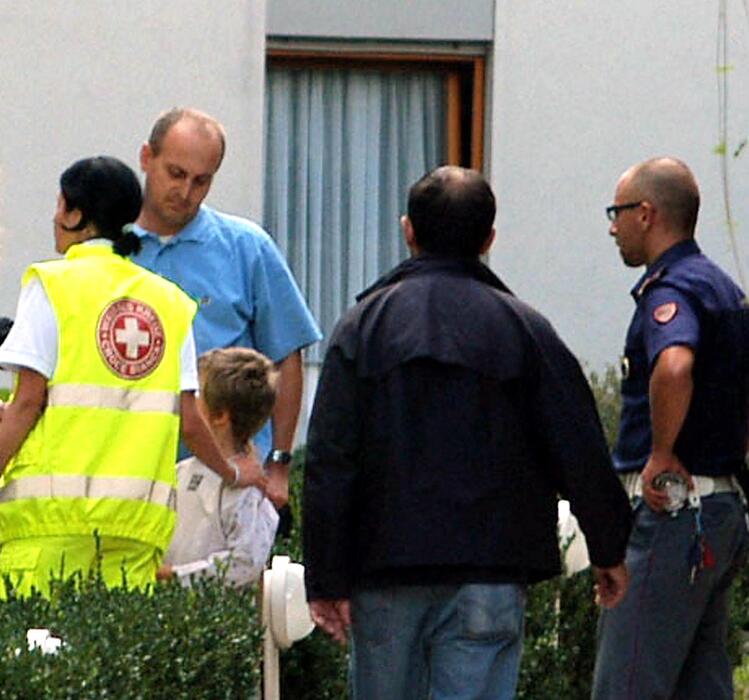In una foto dell'8 settembre 2005 Polizia e personale della croce rossa assistono  Fiorenzo Delladio (secondo da sinistra) e suo figlio, rispettivamente padre e fratello del bimbo di 4 anni pugnalato a morte dalla madre, Christina Rainer, a Merano © 