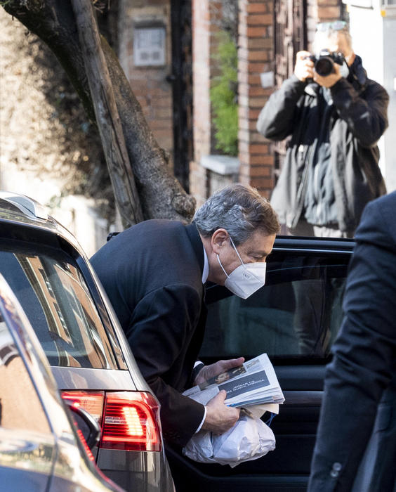 Mario Draghi scende dall'auto a Roma con giornali © 