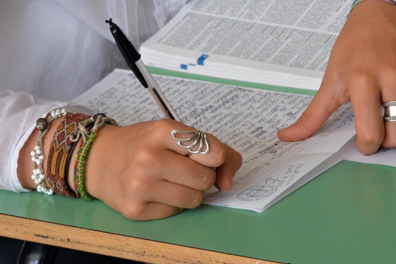 Le mani di una studentessa mentre assiste ad una lezione in classe - RIPRODUZIONE RISERVATA