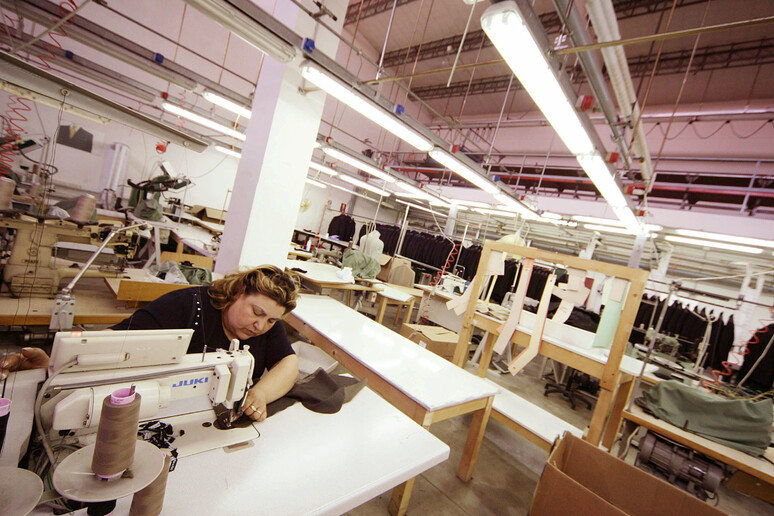 Un 'operaia al lavoro all 'interno  dell 'impresa tessile - RIPRODUZIONE RISERVATA