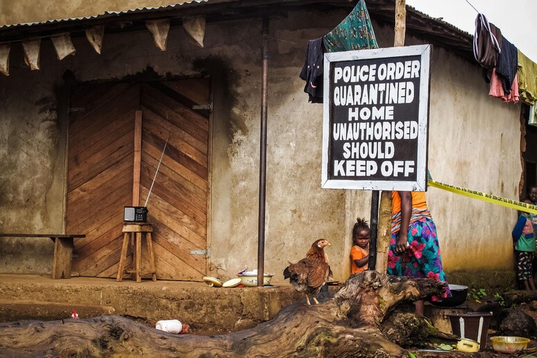 In questa foto d 'archivio relativa al 22 ottobre 2014 un bambino si trova vicino a un cartello che avvisa di una casa in quarantena a Port Loko, in Sierra Leone © ANSA/AP