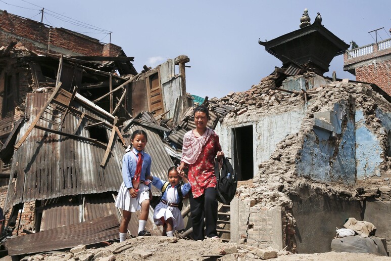 Una mamma con le sue figlie in mezzo alle macerie del terremoto a Kathmandu, Nepal © ANSA/EPA