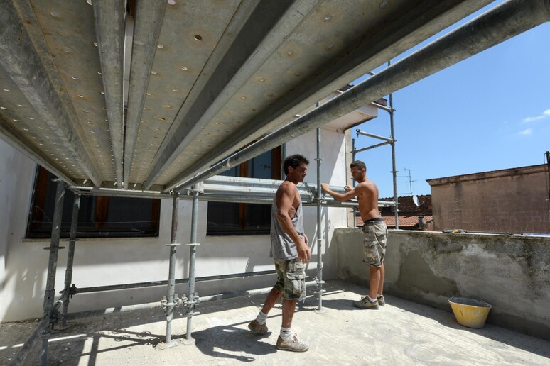 Due operai al lavoro in un cantiere edile a Pisa - RIPRODUZIONE RISERVATA