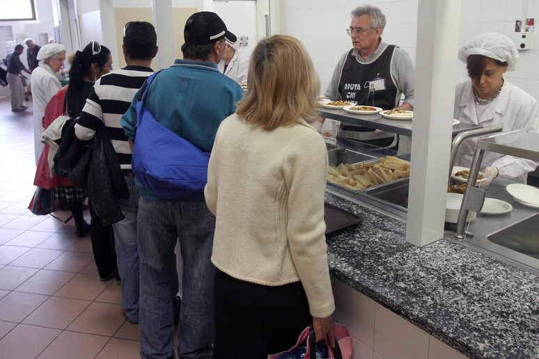 Alcune persone in coda per il pranzo nella mensa per indigenti a Milano - RIPRODUZIONE RISERVATA