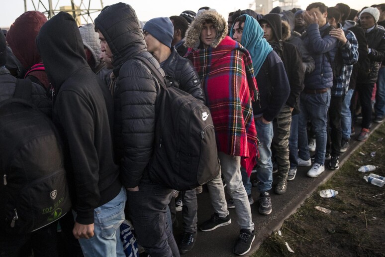 Migranti in attesa di entrare in un centro di accoglienza © ANSA/EPA