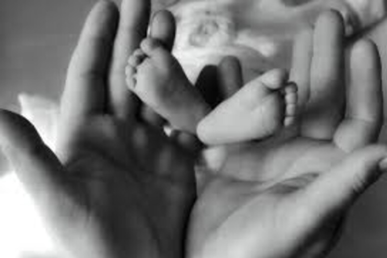 Piedi di un neonato nelle mani di un genitore - RIPRODUZIONE RISERVATA