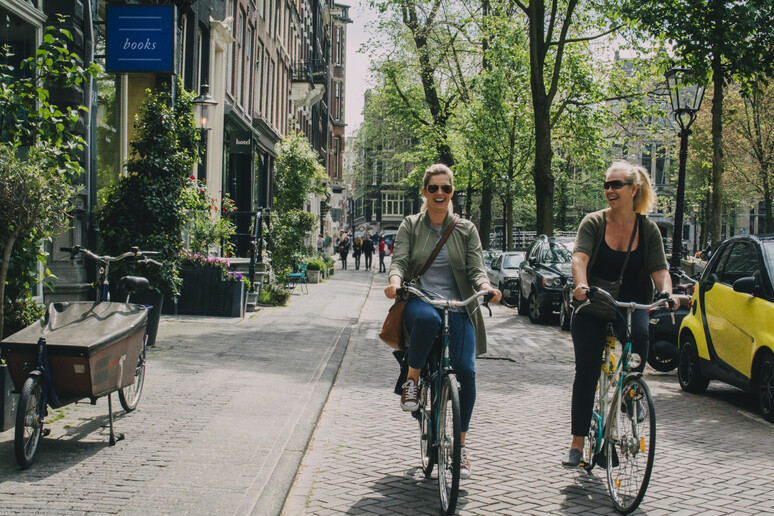 Amsterdam, due cittadine con la bicicletta. foto iStock. - RIPRODUZIONE RISERVATA