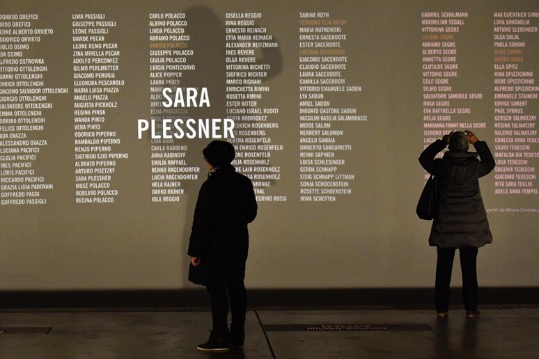 Due donne osservano una parete sulla quale sono proiettati i nomi degli ebrei italiani deportati nei campi di sterminio nazisti al Memoriale della Shoah di Milano - RIPRODUZIONE RISERVATA