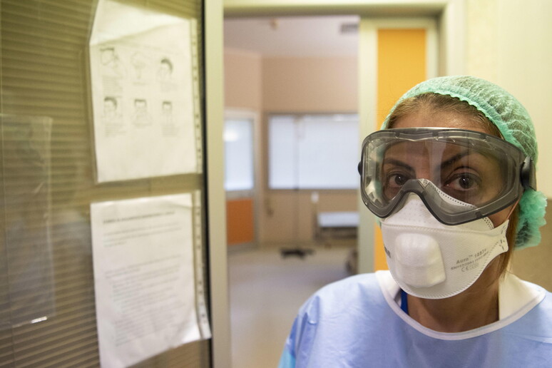 Una dottoressa con maschera e occhiali per proteggersi dall 'emergenza © ANSA/EPA