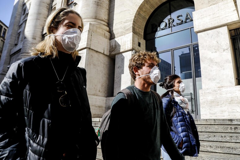 Persone con mascherine davanti all 'ingresso della Borsa a Milano - RIPRODUZIONE RISERVATA