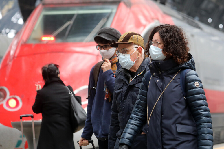 Viaggiatori indossano mascherine protettive - RIPRODUZIONE RISERVATA