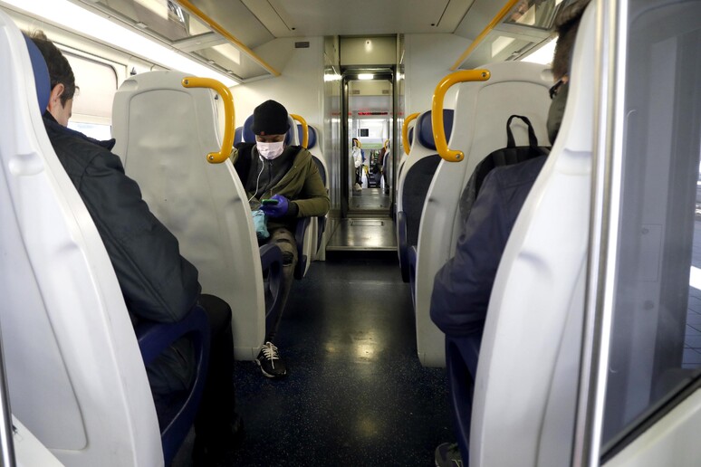 Un uomo con la mascherina su un treno regionale a Milano - RIPRODUZIONE RISERVATA