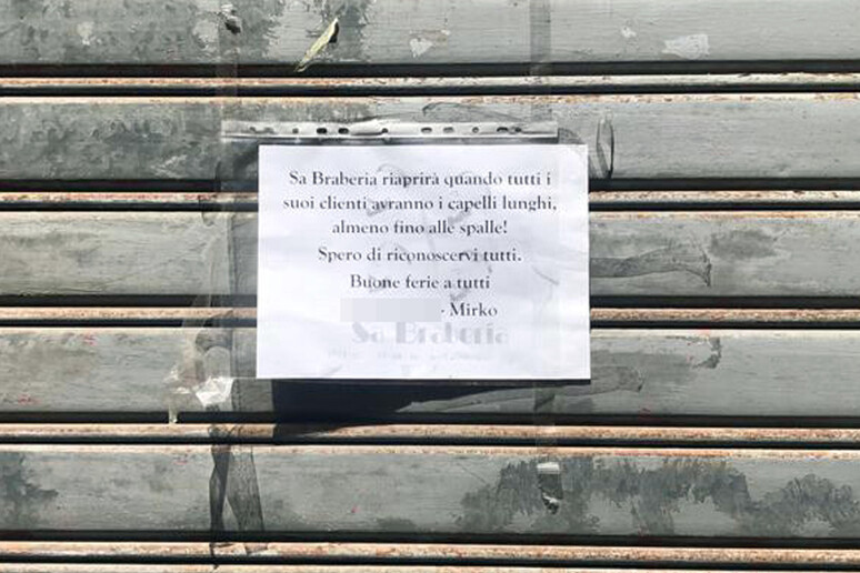 singolare cartello sulla serranda di un barbiere a Cagliari - RIPRODUZIONE RISERVATA