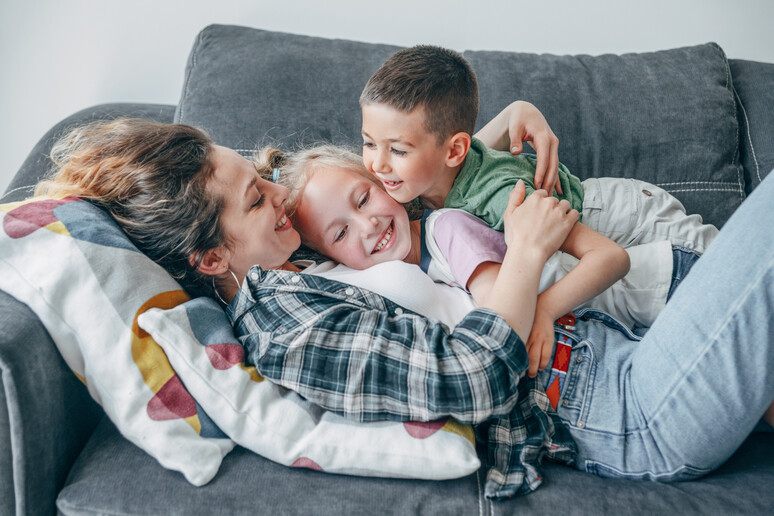 Una mamma abbraccia i due figli foto iStock. - RIPRODUZIONE RISERVATA