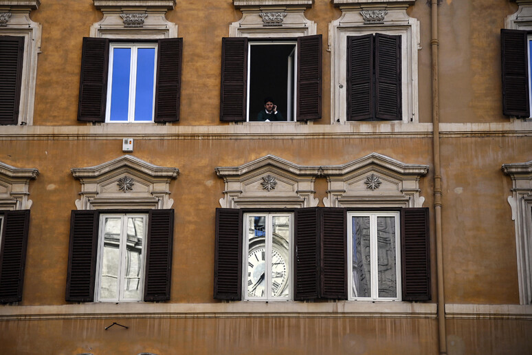 L 	'orologio sulla facciata di Palazzo Montecitorio riflesso nella finestra di un edificio durante le consultazioni del presidente incaricato Fico - RIPRODUZIONE RISERVATA