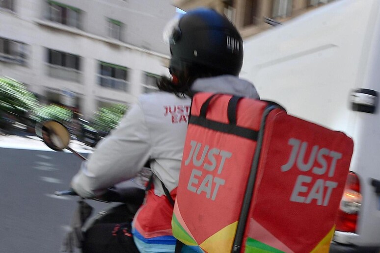 Un rider della Just Eat impegnato in una consegna nel centro di Genova - RIPRODUZIONE RISERVATA