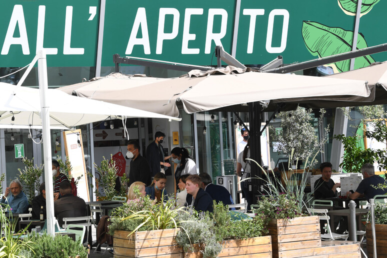Persone pranzano sedute ai tavoli di un bar-ristorante, Milano - RIPRODUZIONE RISERVATA