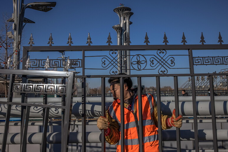 Un operaio monta un cancello davanti alla Olympic Tower di Pechino © ANSA/EPA