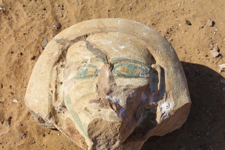 Testa dipinta del coperchio di un sarcofago in pietra, rinvenuto durante una ricognizione nella necropoli dell’Aga Khan (fonte: Piacentini, Università di Milano) - RIPRODUZIONE RISERVATA