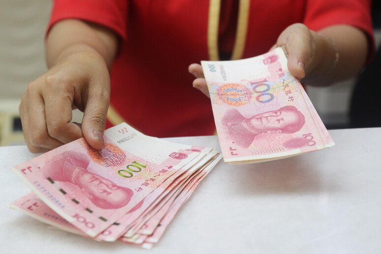 Un 'impiegata conta le banconote yuan © ANSA/EPA