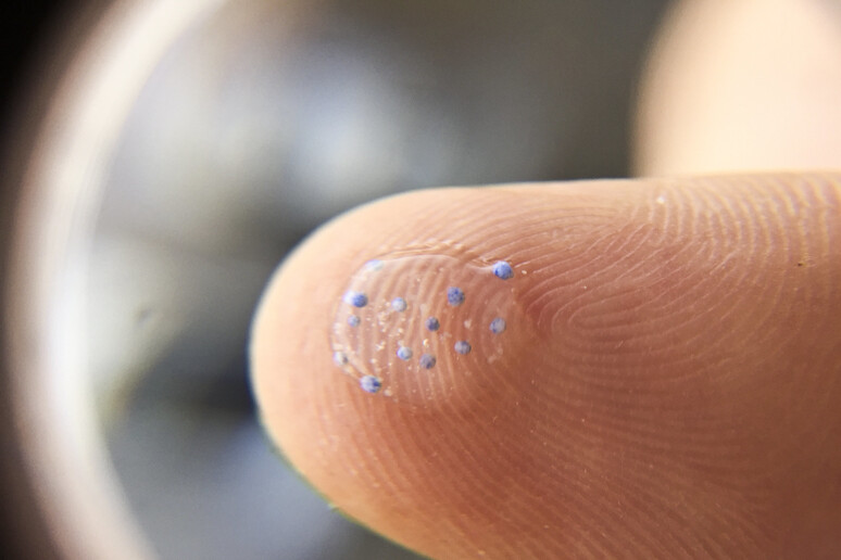 Microplastiche su un polpastrello viste attraverso una lente d 'ingrandimento (fonte: MPCA Photos da Flickr) - RIPRODUZIONE RISERVATA