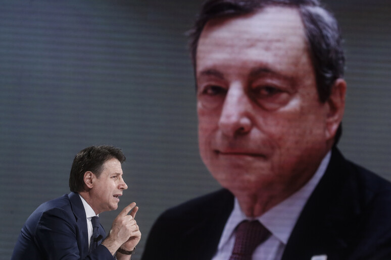 Giuseppe Conte e dietro una foto del premier Mario Draghi - RIPRODUZIONE RISERVATA