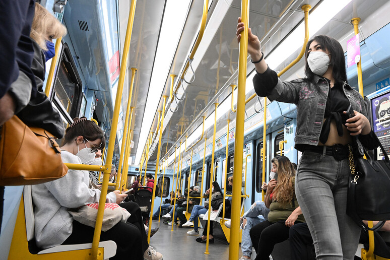 Persone indossano mascherine sanitarie in un vagone della metropolitana a Milano - RIPRODUZIONE RISERVATA