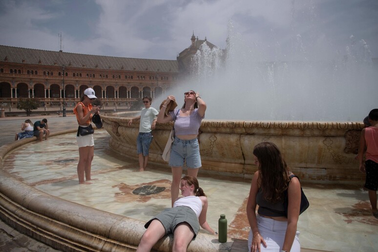 Persone si rinfrescano con l 'acqua di una fontana durante l 'ondata di caldo a Siviglia. © ANSA/AFP