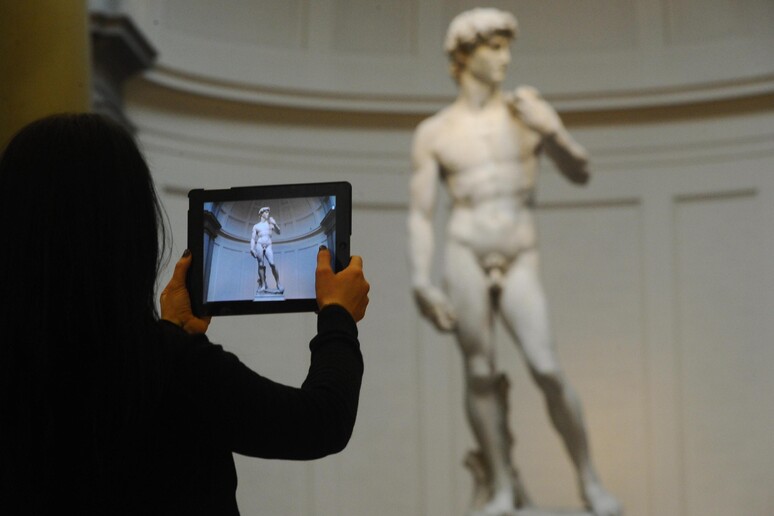 Un visitatore scatta una foto del David di Michelangelo presso la galleria dell 'Accademia di Firenze - RIPRODUZIONE RISERVATA